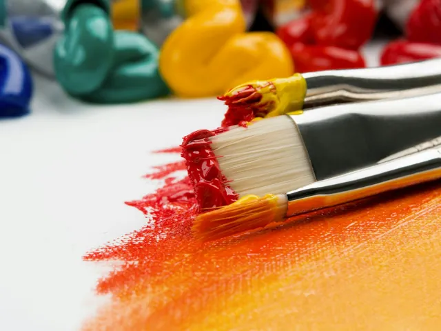 Paintbrushes and vivid colours on an artist’s worktable